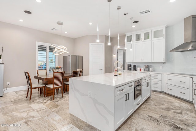 kitchen with visible vents, stainless steel oven, wall chimney exhaust hood, backsplash, and a center island