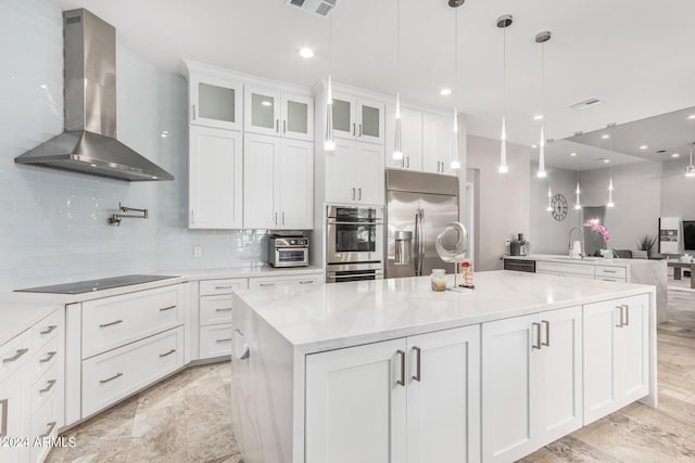 kitchen with tasteful backsplash, a kitchen island, open floor plan, appliances with stainless steel finishes, and wall chimney exhaust hood