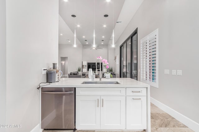 kitchen with baseboards, a sink, white cabinets, stainless steel dishwasher, and open floor plan