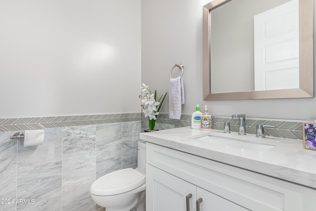 bathroom with tile walls, a wainscoted wall, toilet, and vanity