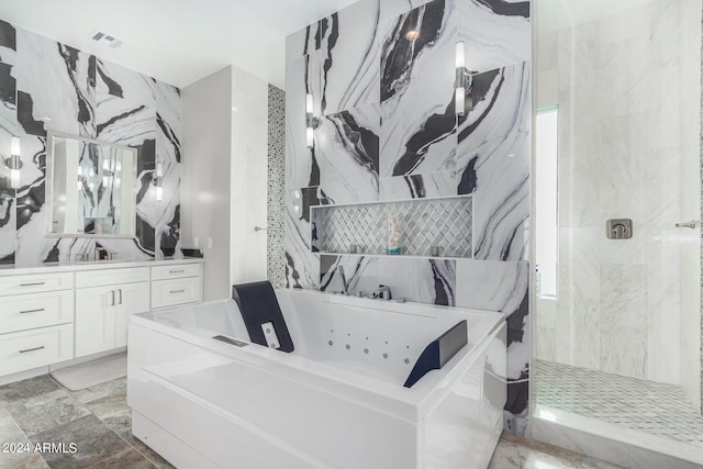 full bath featuring vanity, a tub with jets, visible vents, a walk in shower, and tile walls