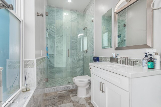 bathroom with a shower with door, vanity, tile patterned floors, and toilet