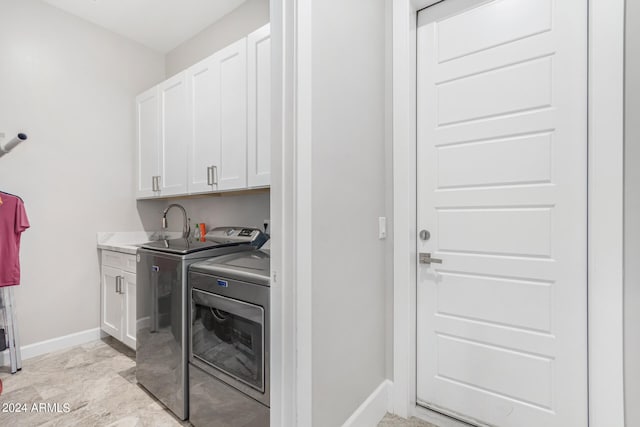 laundry room with washer and clothes dryer, cabinets, and light tile patterned floors