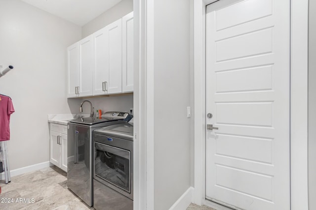 washroom featuring cabinet space, washer and dryer, baseboards, and a sink