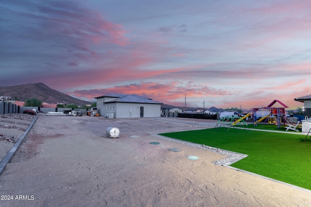 exterior space with a mountain view, a playground, and a lawn