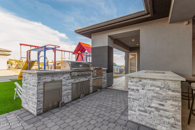 view of patio / terrace with a playground, grilling area, and exterior kitchen