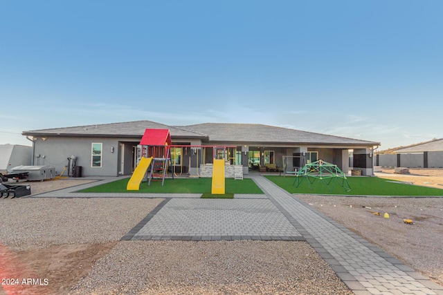 view of front of property with a patio, a front yard, playground community, and stucco siding