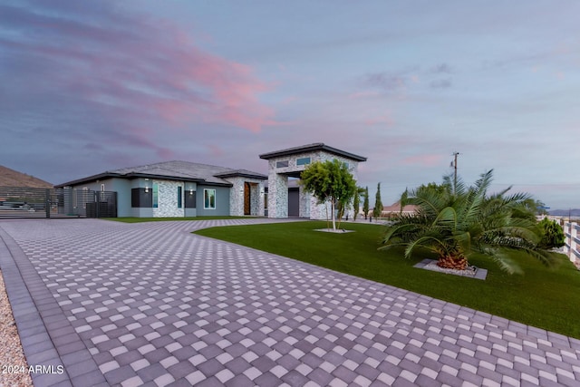 view of front facade with decorative driveway, stone siding, a front lawn, and stucco siding