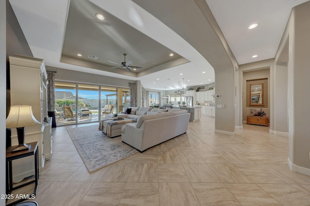 living room with a raised ceiling and ceiling fan