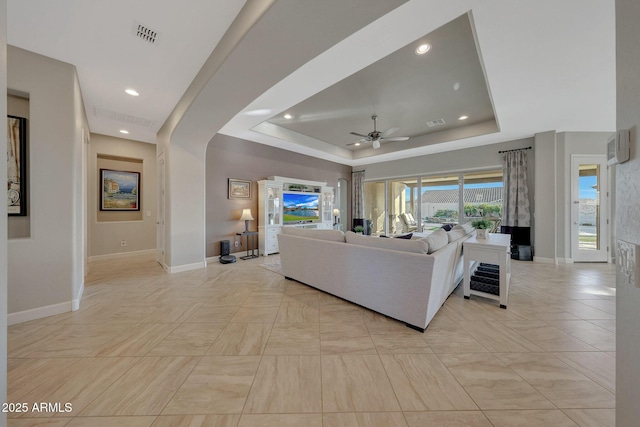 living room featuring ceiling fan and a tray ceiling