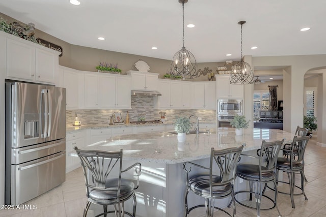 kitchen featuring white cabinets, pendant lighting, stainless steel appliances, a large island, and backsplash