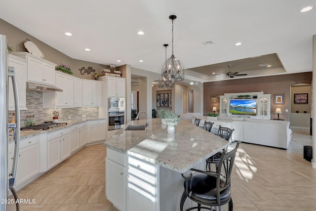 kitchen featuring sink, appliances with stainless steel finishes, white cabinetry, a spacious island, and a kitchen bar