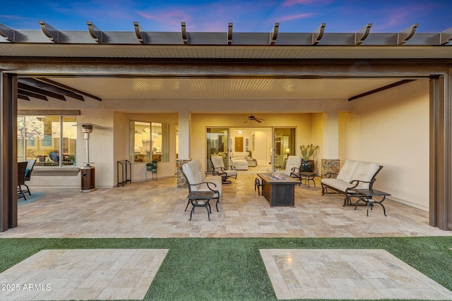 patio terrace at dusk with ceiling fan and an outdoor fire pit