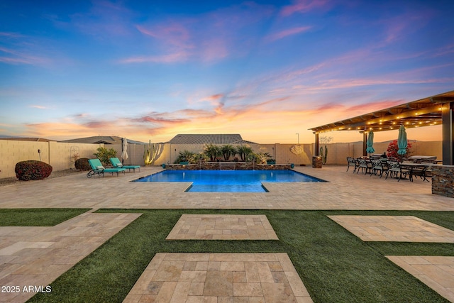 pool at dusk with a patio area