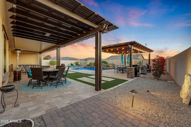 patio terrace at dusk featuring a pergola, a fenced in pool, and a mountain view