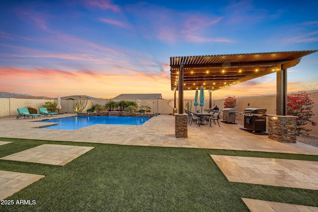 pool at dusk featuring a grill, a pergola, a patio, and exterior kitchen