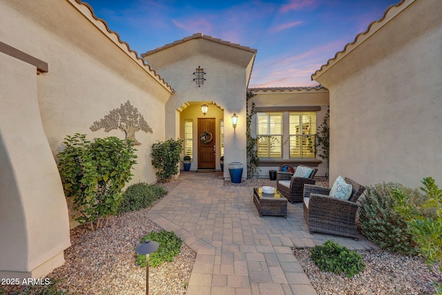 exterior entry at dusk with an outdoor living space and a patio area