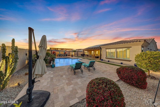 pool at dusk with a pergola and a patio area