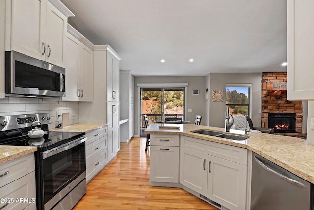809 W St Moritz Dr, Payson, AZ 85541 - kitchen featuring decorative backsplash, light wood-style flooring, a stone fireplace, appliances with stainless steel finishes, and a sink