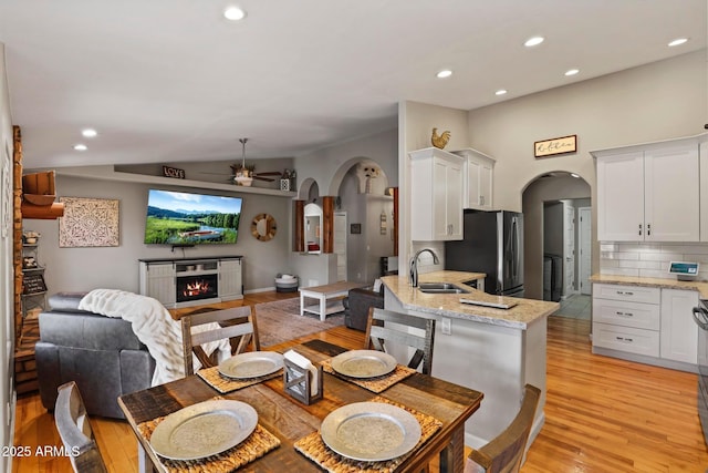 809 W St Moritz Dr, Payson, AZ 85541 - dining area featuring a warm lit fireplace, ceiling fan, arched walkways, lofted ceiling, and light wood-type flooring