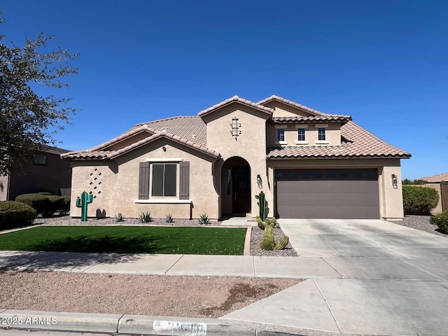 mediterranean / spanish house featuring stucco siding, driveway, a front lawn, a tile roof, and a garage