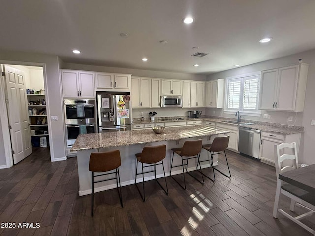 kitchen featuring a kitchen island, stainless steel appliances, dark wood-type flooring, and a sink