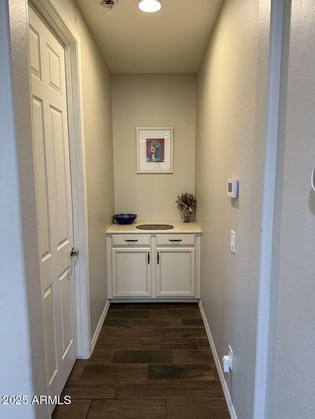 hall with dark wood-style floors and baseboards