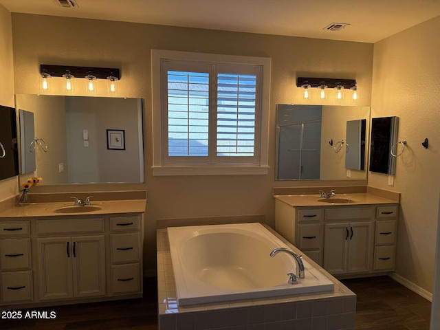 bathroom with a sink, a garden tub, and two vanities