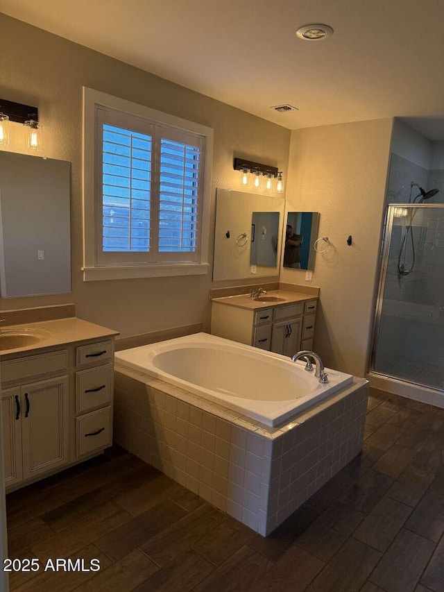 full bath with a bath, a sink, a stall shower, and wood finished floors