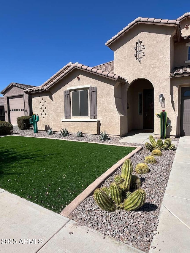 mediterranean / spanish house with a front yard, a tile roof, and stucco siding