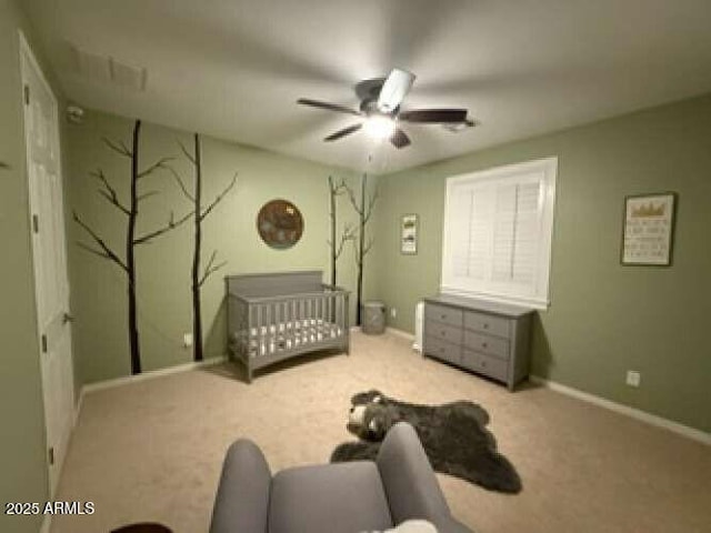 bedroom with a crib, a ceiling fan, baseboards, and carpet floors