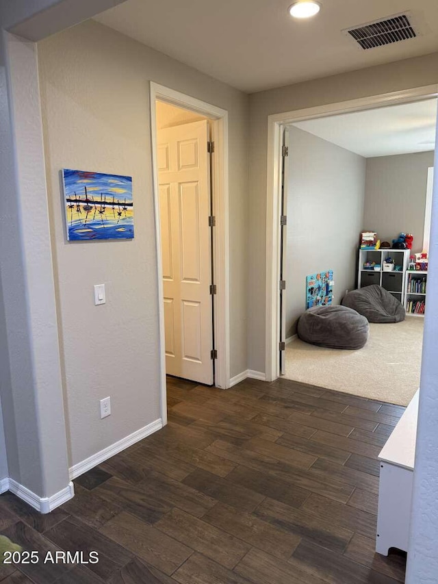 hall featuring baseboards, visible vents, and dark wood-style flooring