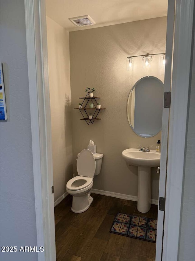 bathroom with visible vents, toilet, baseboards, and wood finished floors