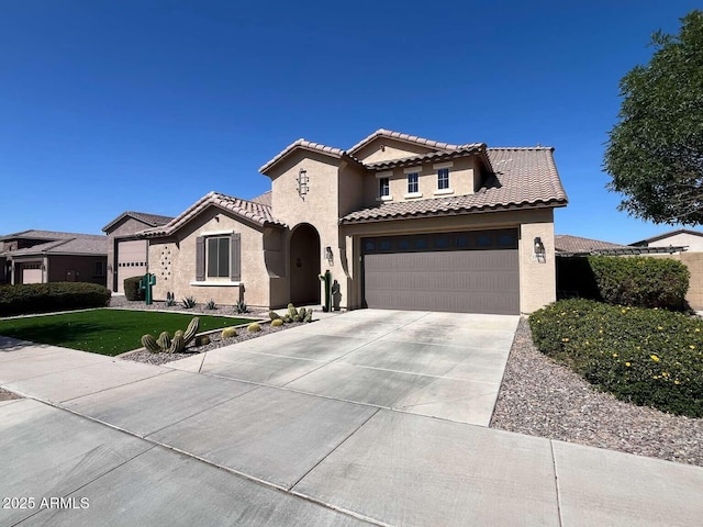 mediterranean / spanish home featuring a front yard, an attached garage, stucco siding, concrete driveway, and a tiled roof