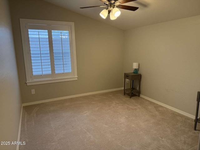 empty room with vaulted ceiling, carpet flooring, a ceiling fan, and baseboards