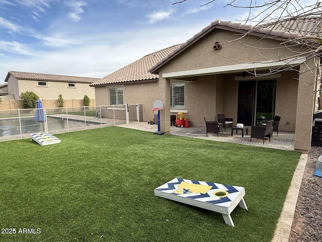 rear view of property featuring stucco siding, a patio, a lawn, and fence