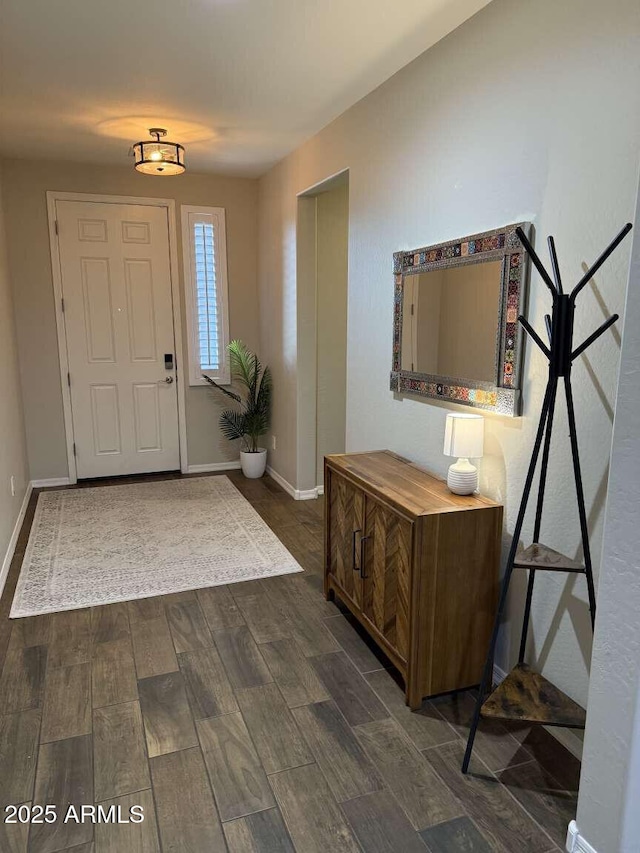 foyer with dark wood-style floors and baseboards