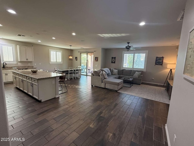 living area featuring visible vents, baseboards, dark wood finished floors, recessed lighting, and a ceiling fan