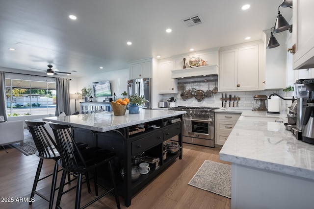 kitchen with light stone counters, appliances with stainless steel finishes, a kitchen island, and white cabinets