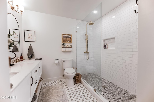 bathroom featuring vanity, a tile shower, and toilet