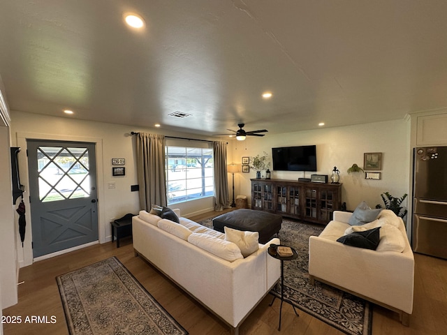 living room featuring dark wood-type flooring and ceiling fan