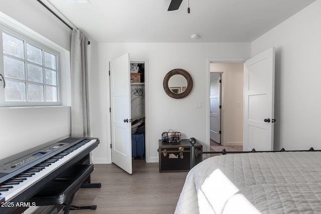 bedroom with hardwood / wood-style flooring, a spacious closet, ceiling fan, and a closet