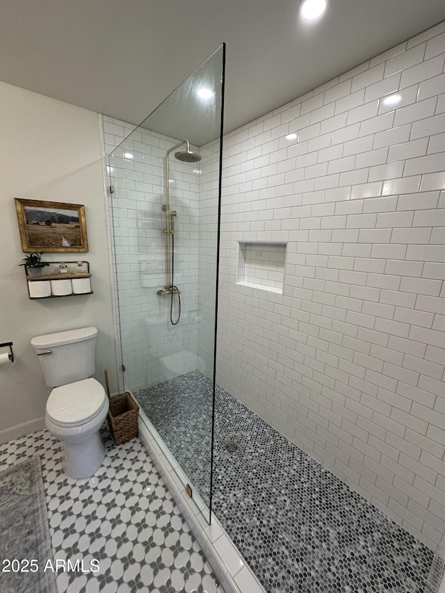 bathroom featuring a tile shower and toilet