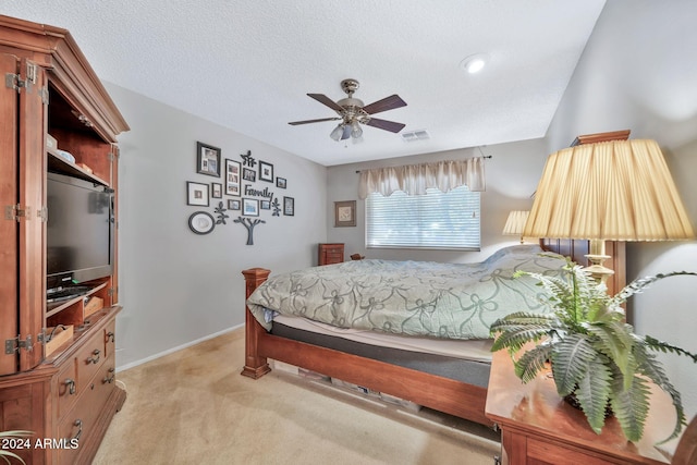 carpeted bedroom featuring ceiling fan and a textured ceiling