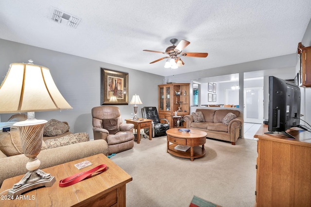 living room featuring light carpet, ceiling fan, and a textured ceiling