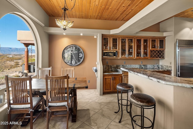 dining area with a mountain view, wet bar, wood ceiling, and light tile patterned flooring