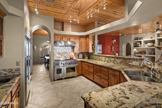 kitchen with light stone countertops, wood ceiling, decorative backsplash, double oven range, and sink