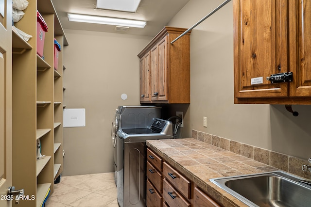 laundry room featuring cabinets, light tile patterned floors, washer and clothes dryer, and sink