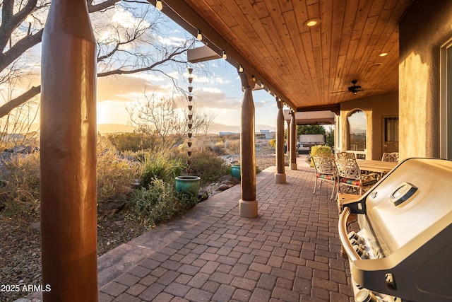 patio terrace at dusk with ceiling fan and a grill