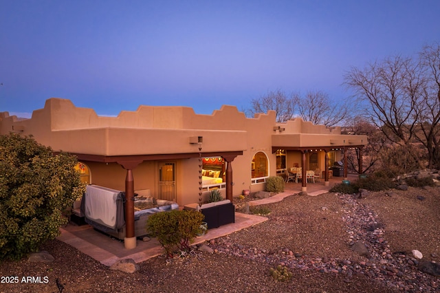 back house at dusk with an outdoor hangout area and a patio